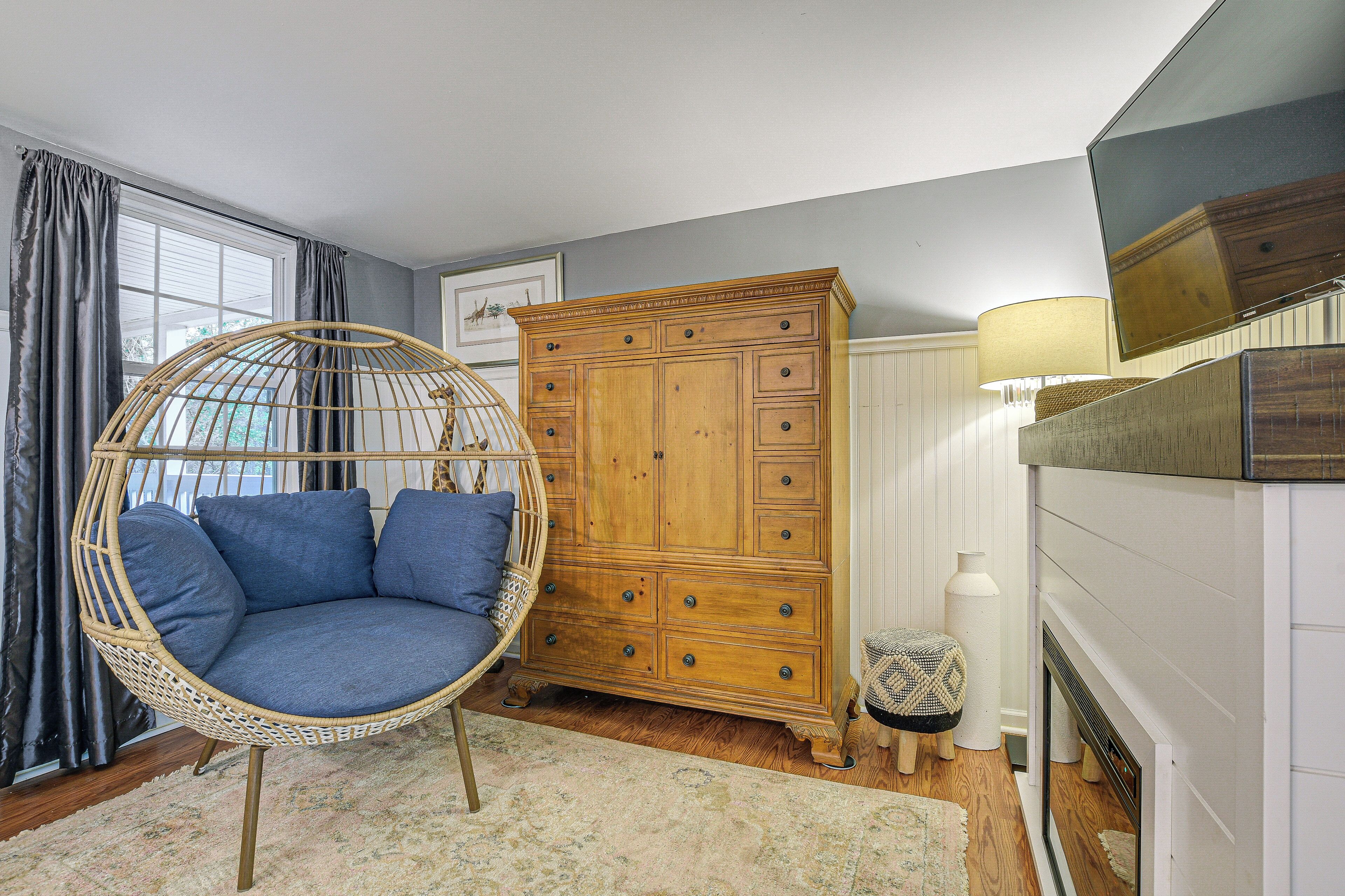 A room with a hanging chair, wooden cabinet, and a fireplace.