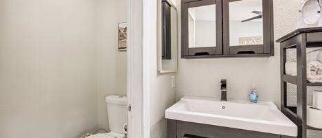A bathroom with a white toilet, a white sink, and a dark wooden vanity.