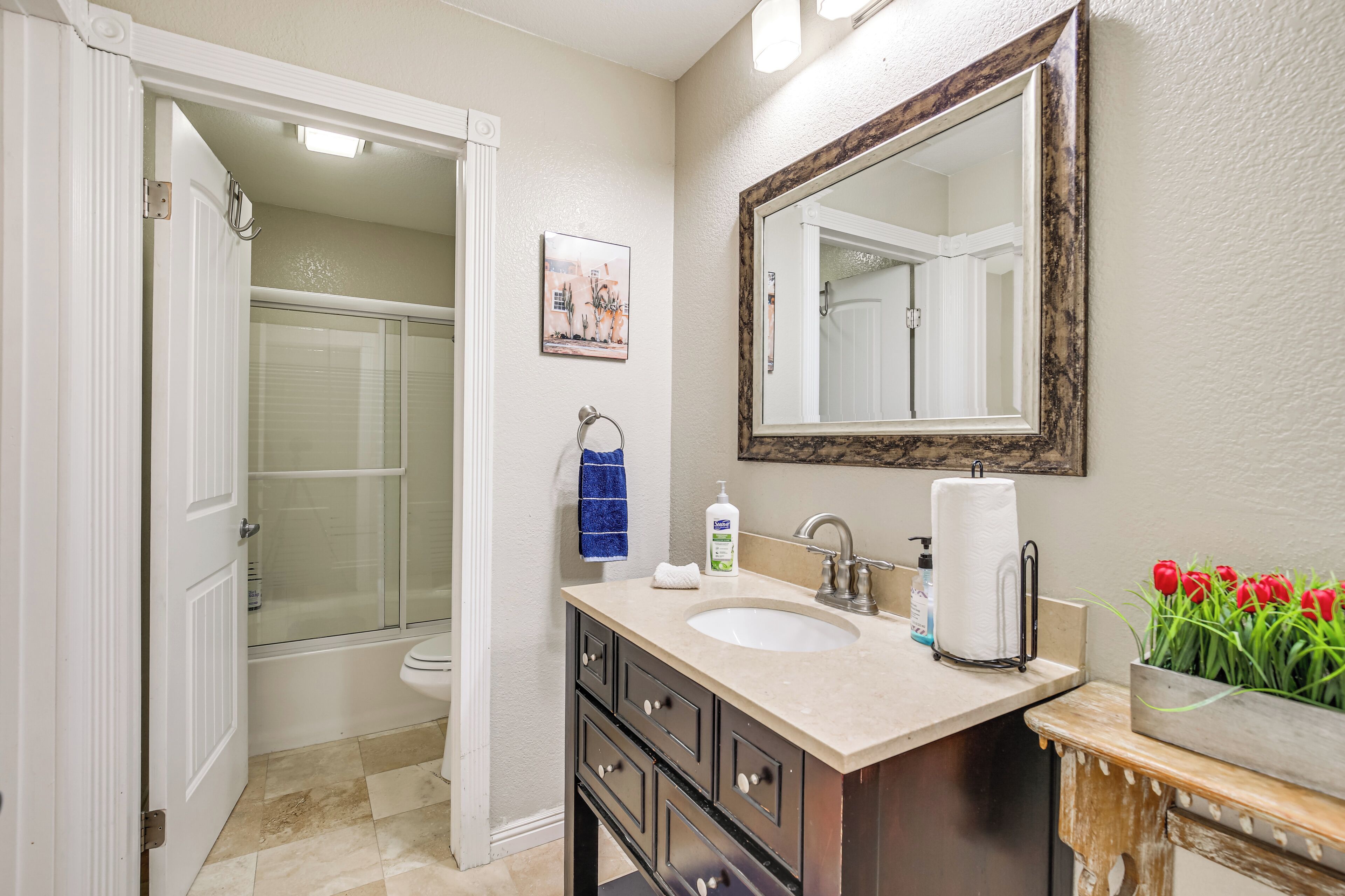 A bathroom with a sink, mirror, and shower.