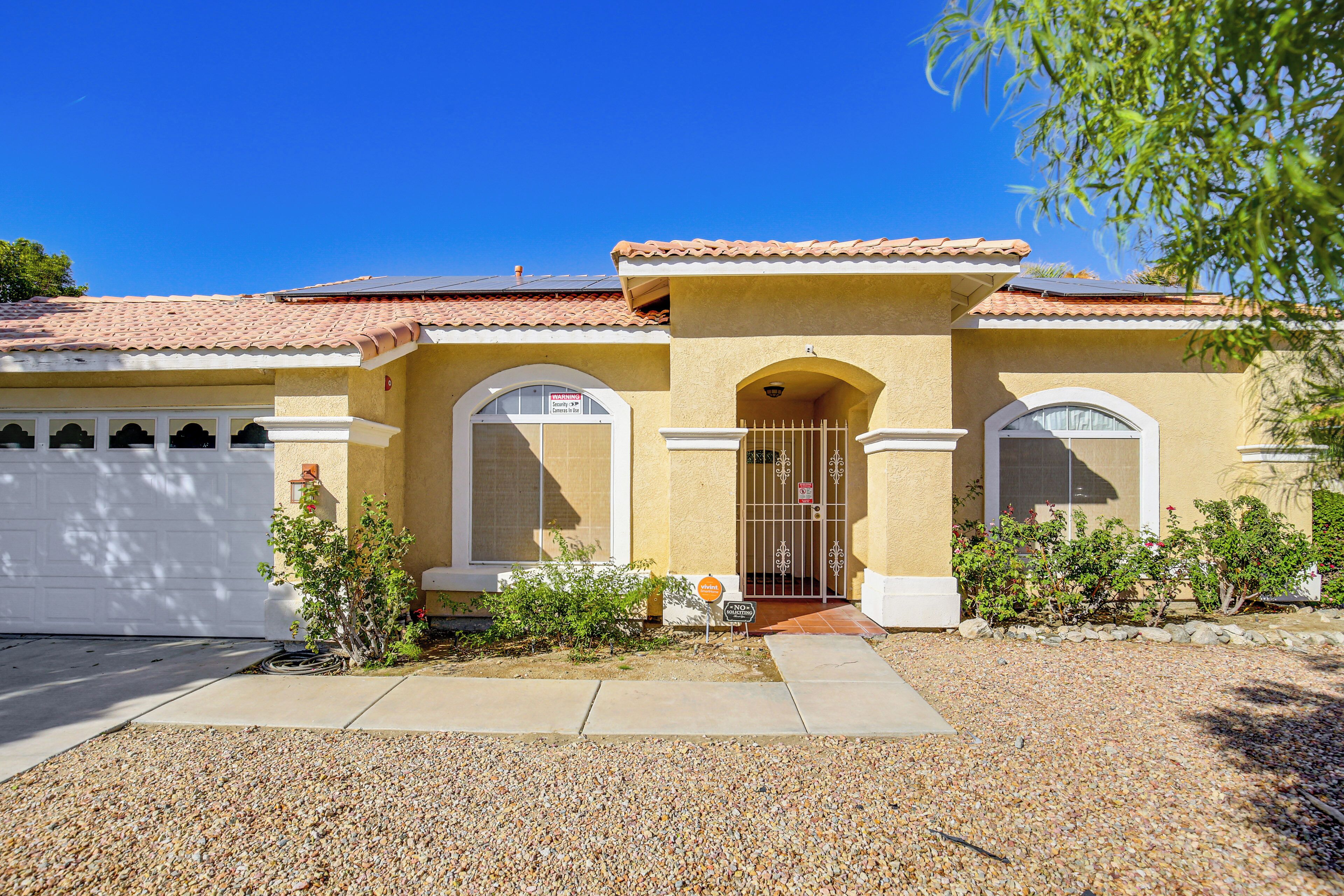 A two-story house with a tiled roof, a garage, and a front entrance with a gate.