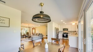A modern kitchen with white cabinets, stainless steel appliances, and a dining area with a wooden table and chairs. - Fire Pit & Grill: Tyler Home on 5 Acres! (Tyler)
