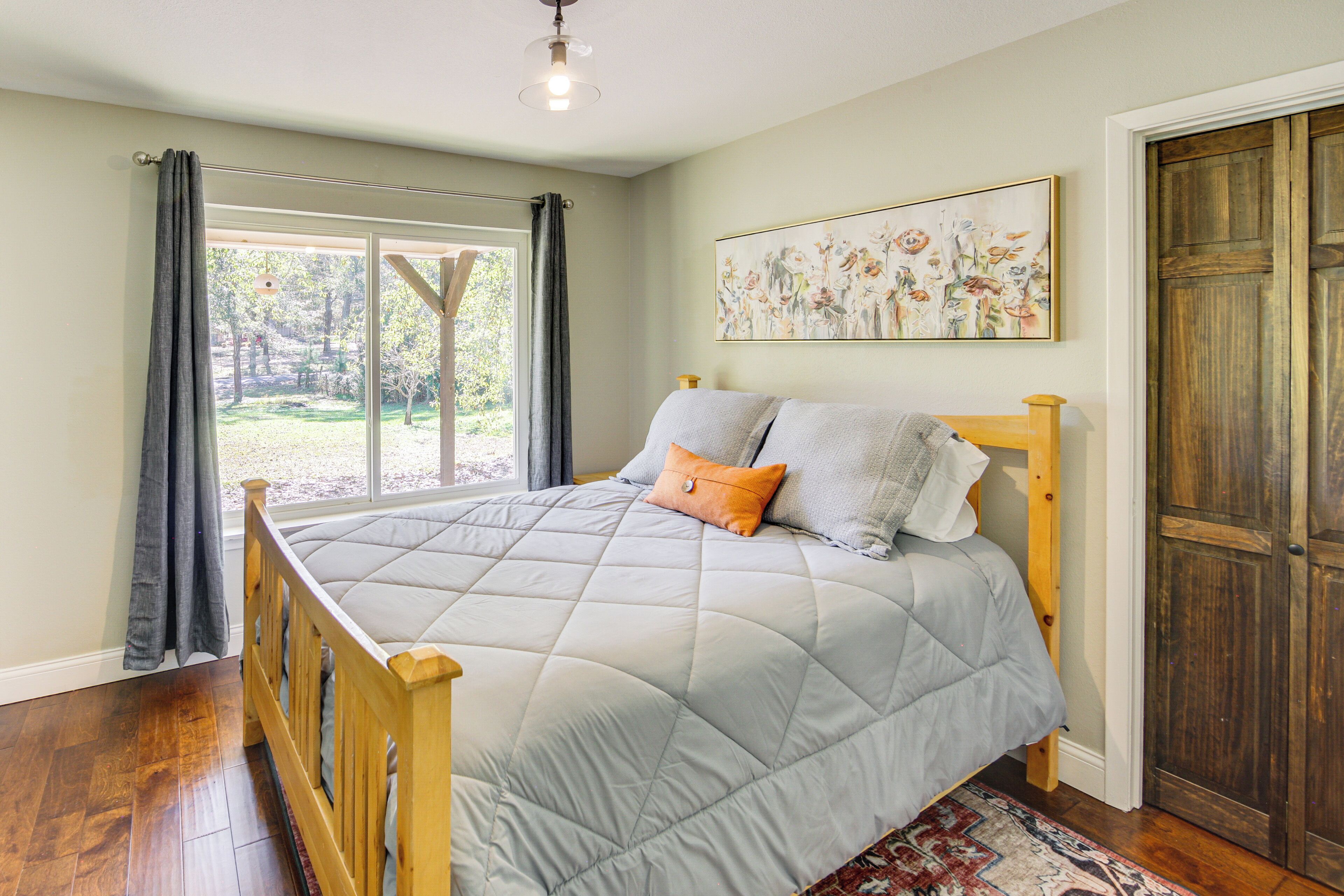 Une chambre avec un lit en bois, une vue sur l’extérieur et une porte située sur le côté droit.