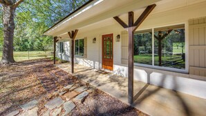 A covered porch with stone steps, wooden beams, and a view of a grassy yard. - Fire Pit & Grill: Tyler Home on 5 Acres! (Tyler)
