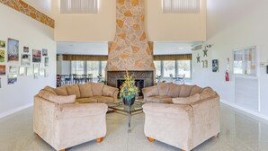 A spacious lobby with two beige sofas, a stone fireplace, and a glass coffee table.