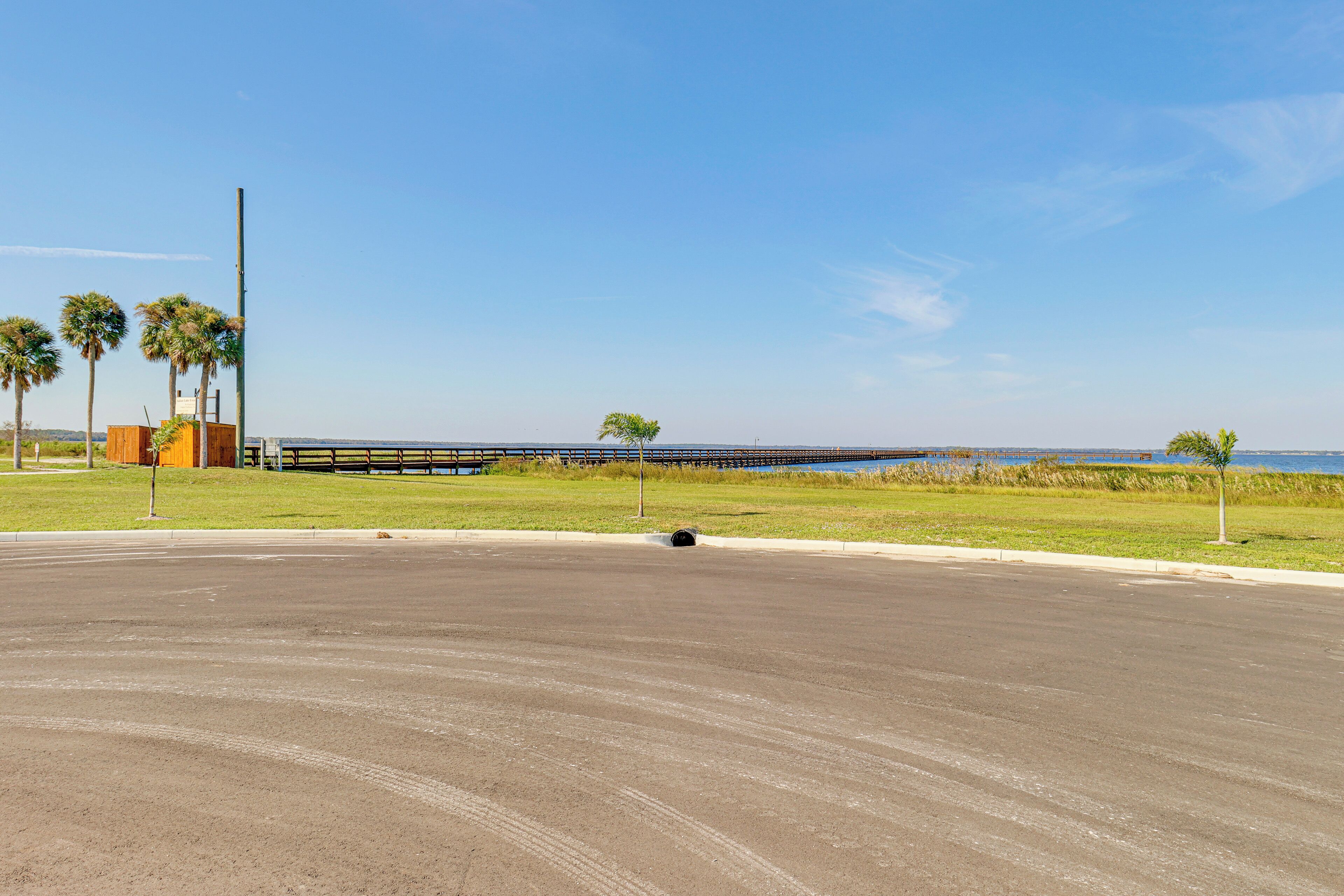 A wide, empty road with a grassy area and a few trees on the side.