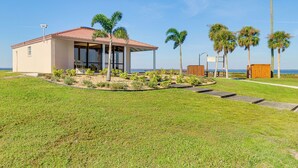 A modern building with a red roof, surrounded by a well-maintained lawn and palm trees.