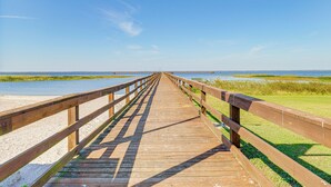 A wooden boardwalk leading to a beach with a clear sky.