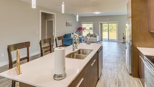 A modern kitchen with a large island, stainless steel appliances, and pendant lighting.