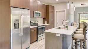 A modern kitchen with stainless steel appliances, wooden cabinets, and a central island with bar stools.