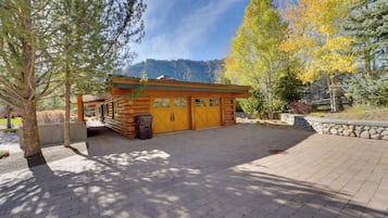 Escape to a serene mountain retreat surrounded by mature trees and a forested backdrop.