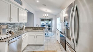 A modern kitchen with white cabinetry, stainless steel appliances, and a granite countertop. - On-site Canal Access: Luxe Home in Palm Coast! (Palm Coast)