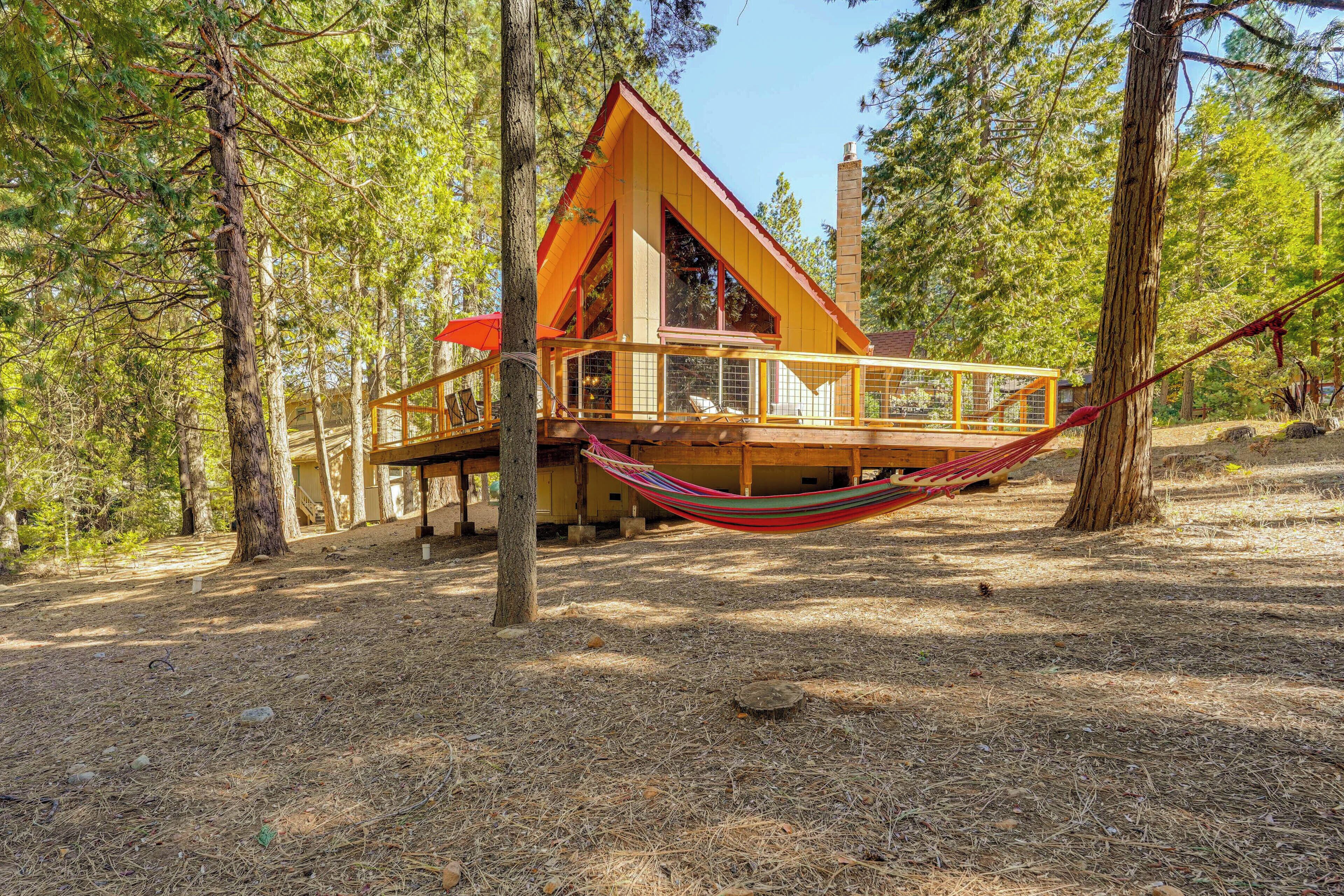 Une cabane en bois dotée d’un balcon, entourée d’arbres.