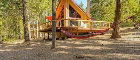Une cabane en bois dotée d’un balcon, entourée d’arbres.