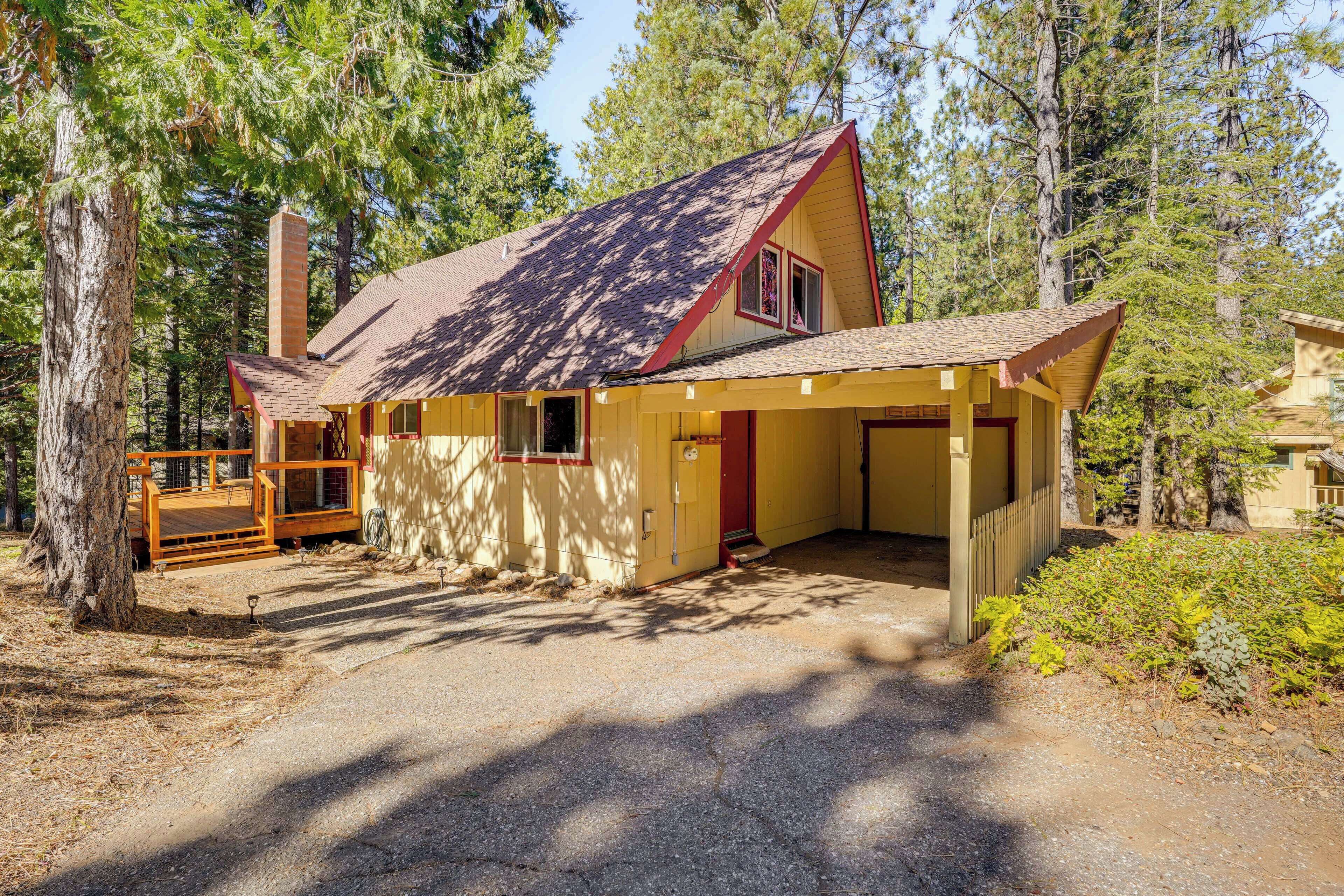 Une cabane dotée d’une terrasse en bois, d’une cheminée et d’un porche abrité.
