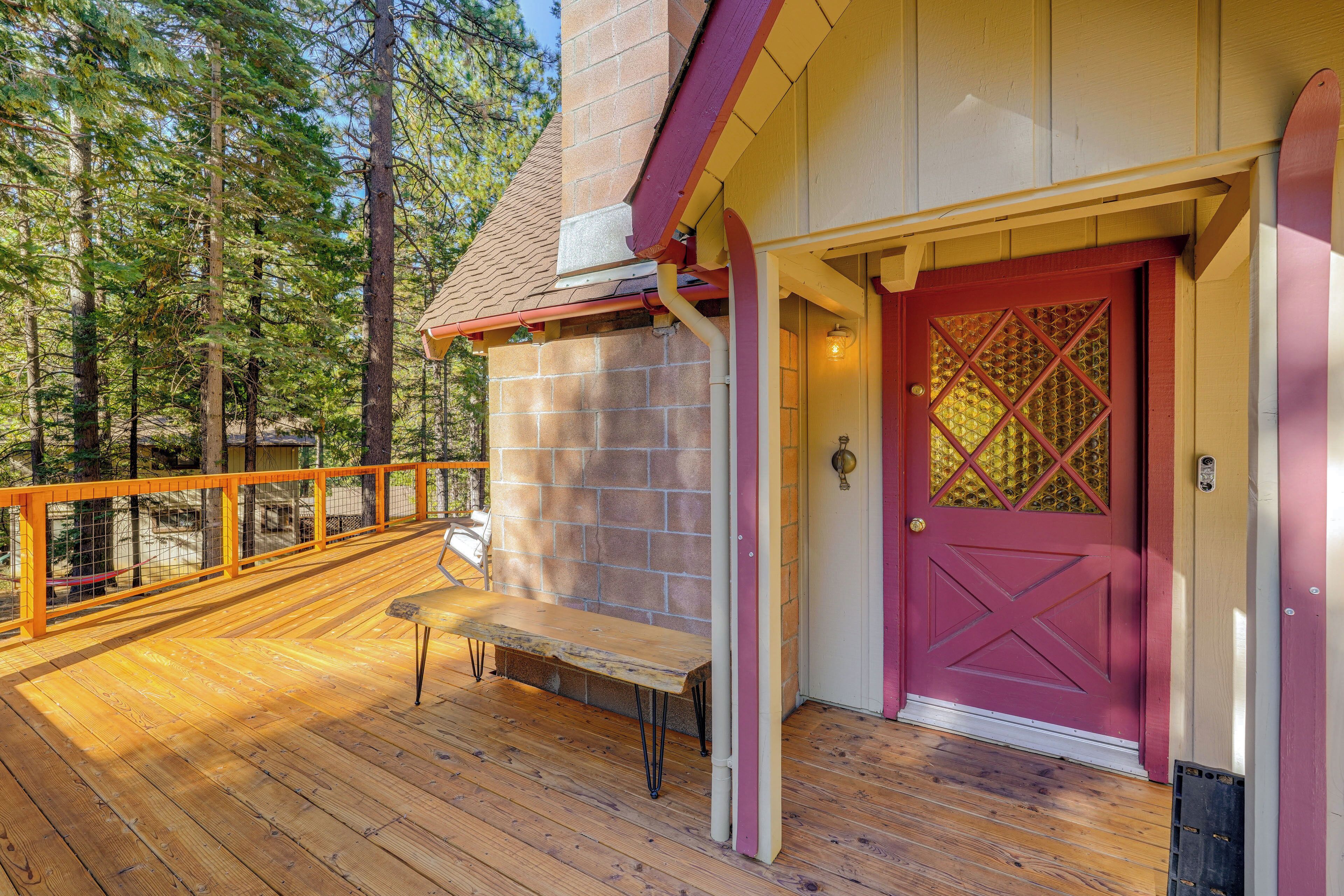 A wooden deck with a bench and a red door with a diamond-patterned window.