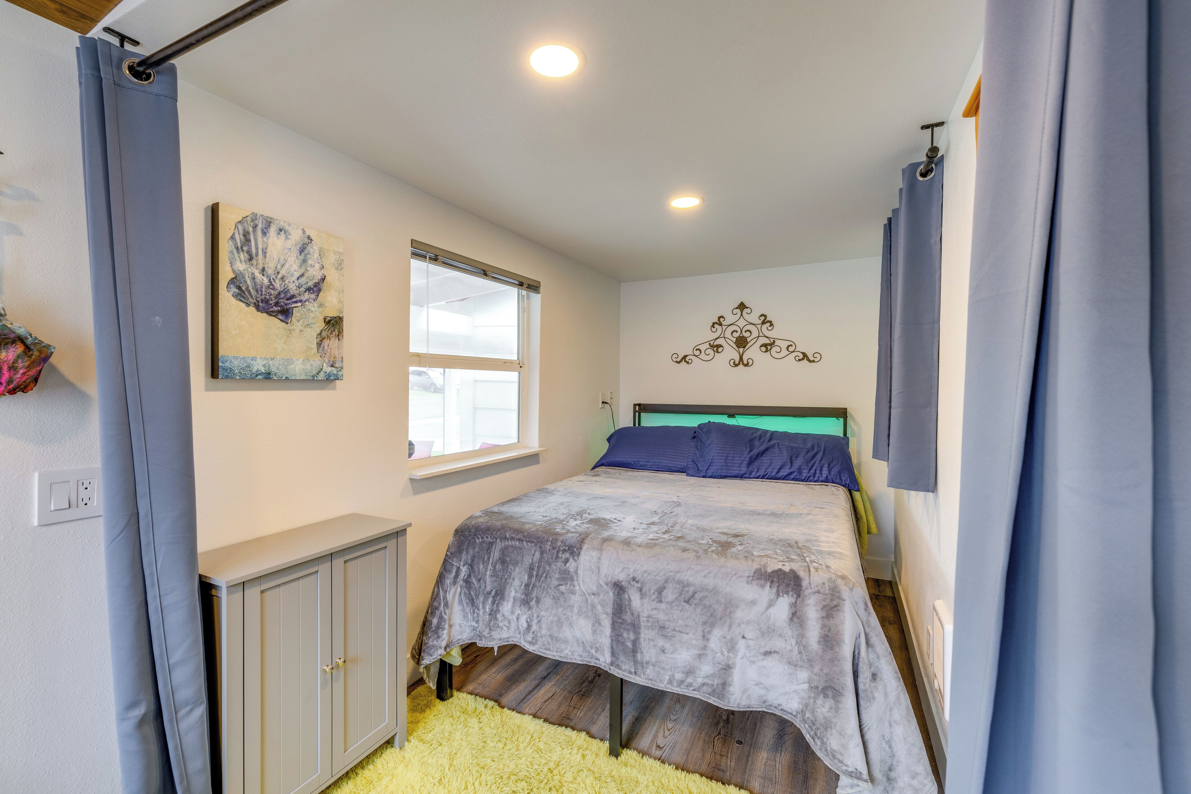 A bedroom with a bed, a window, a wall decoration, and a cabinet.