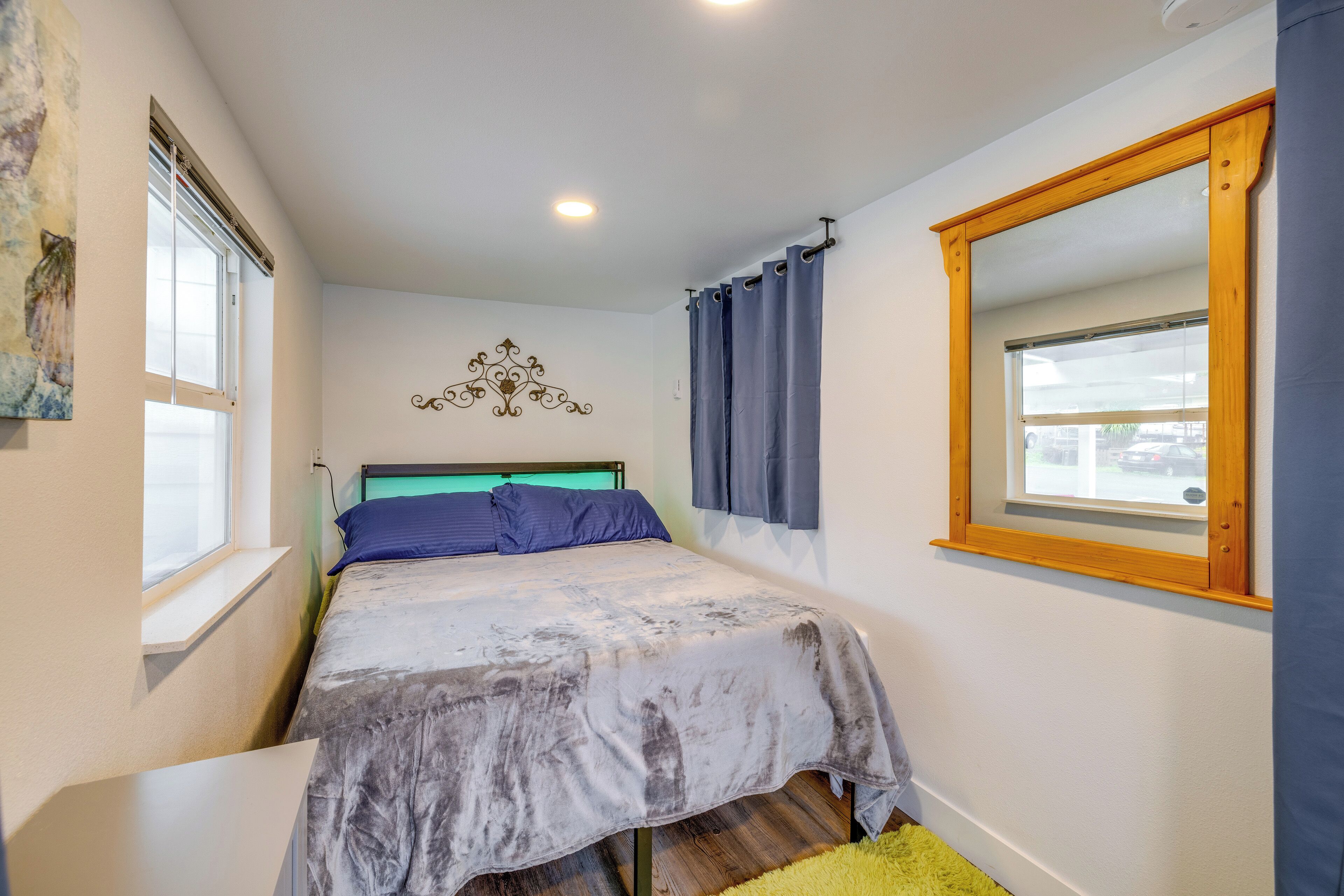 Une chambre à coucher avec un lit, une fenêtre, un rideau et un élément de décoration fixé au mur.
