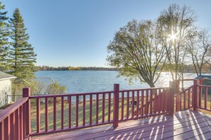 Ein Holzdeck mit roter Geländer, das auf einen See blickt.