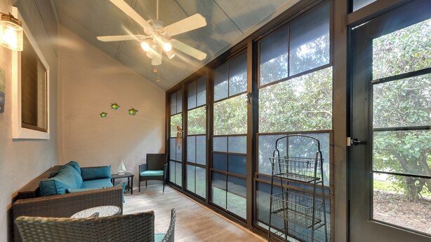 A room with a large window, wicker furniture, a ceiling fan, and a metal shelf. - Golf Getaway w/ Pool Access: Little River Home! (Little River)