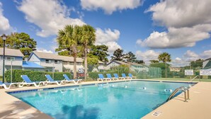 A swimming pool with blue water, surrounded by lounge chairs and palm trees. - Golf Getaway w/ Pool Access: Little River Home! (Little River)
