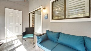 A room with a blue sofa, a wicker chair, a white door, and a window with blinds. - Golf Getaway w/ Pool Access: Little River Home! (Little River)