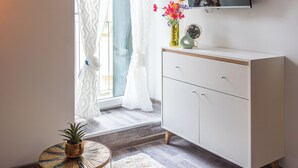 A room with a white cabinet, a small round table with a plant, a TV on the wall, and a window with curtains. - [Piazza Erbe] In city center up to 4 guests with parking (Verona)