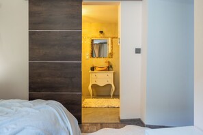 A bedroom with a bed, a wooden wardrobe, a bathroom with a sink and mirror, and a white rug. - [Piazza Erbe] In the city center, accommodates up to 4 guests, with parking (Verona)