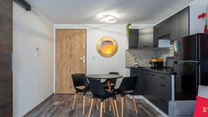 A modern kitchen with dark cabinets, a round dining table with black chairs, and a red cushion on a grey sofa. - [Piazza Erbe] In city center up to 4 guests with parking (Verona)