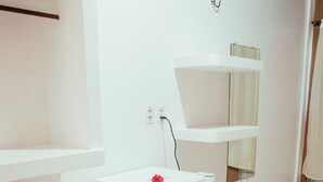 Ein helles, weißes Badezimmer mit einer kleinen, weißen Waschmaschine, einem Handtuchhalter und einem Regal mit einem Spiegel.