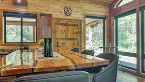 A wooden interior with a large dining table, chairs, and large windows offering a view of the forest. - Galena Cabin on 20 Acres: 5 Mi to Downtown! (Galena)