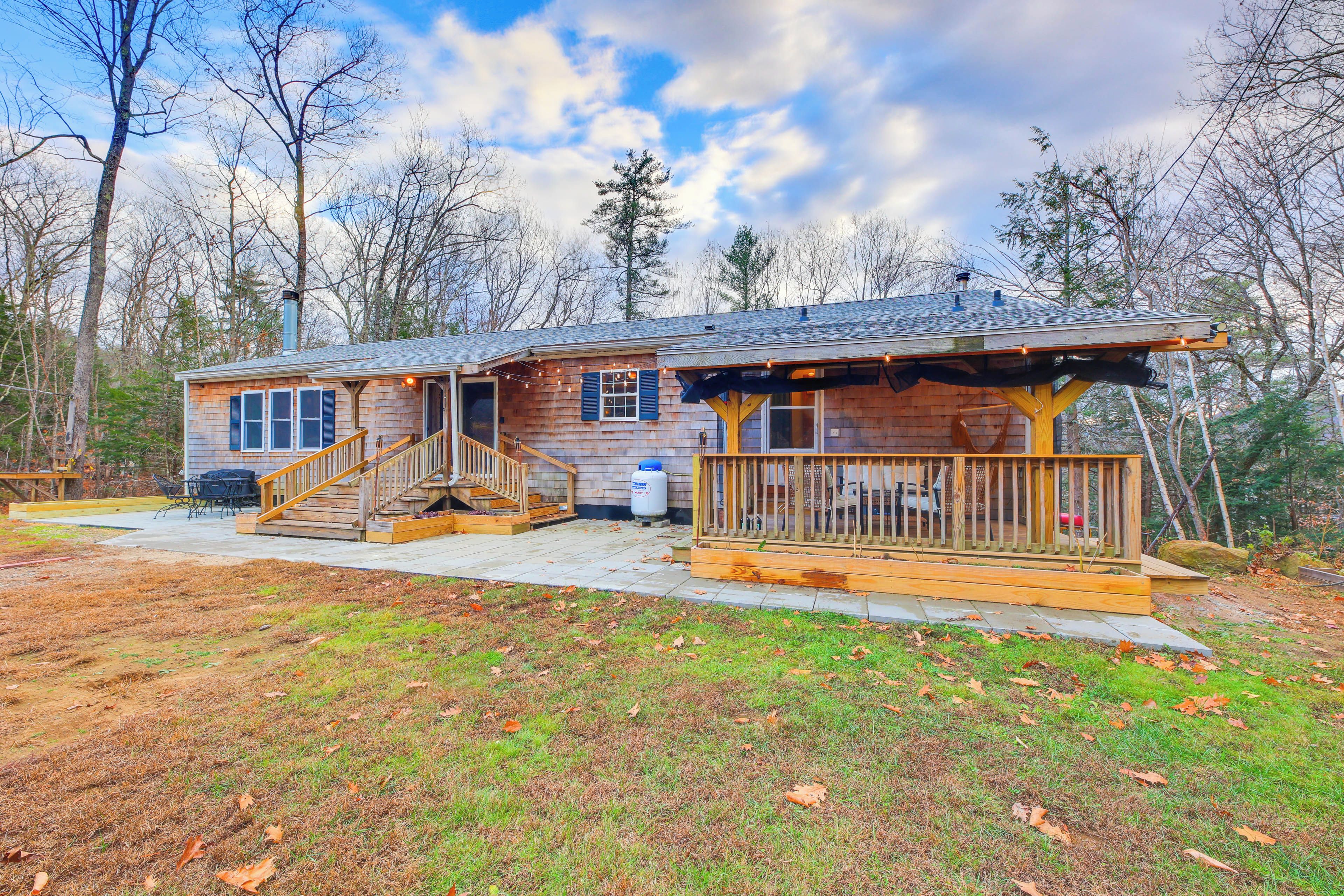 A wooden cabin with a porch, a staircase, and a patio area.
