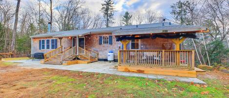 A wooden cabin with a porch, a staircase, and a patio area.