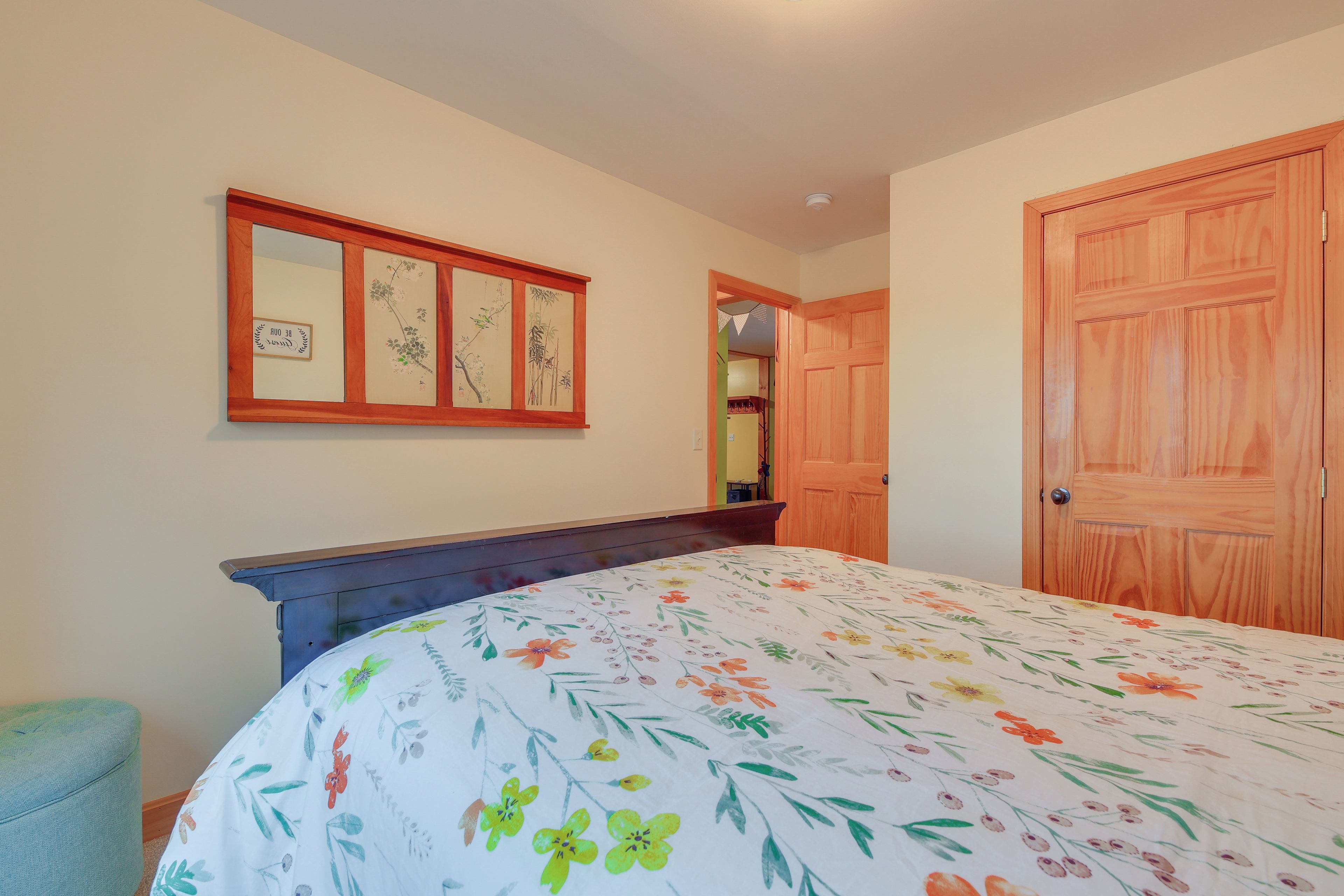 Een slaapkamer met een bed, een houten deur en een spiegel aan de muur.