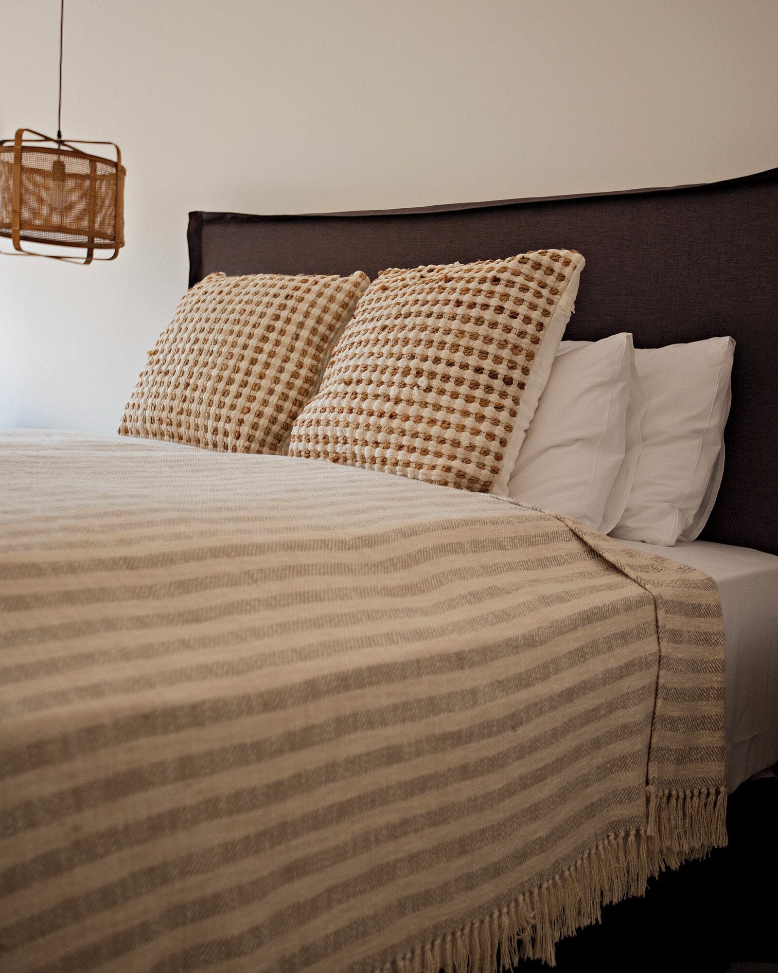A bed with a striped blanket, two textured pillows, and a dark headboard.