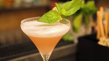 Un cóctel en una copa de martini con una guarnición, sobre una barra de madera.