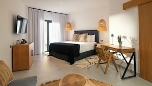 A modern hotel room with a large bed, a desk, a TV, and a dining area. - ALCAIDESA BOUTIQUE HOTEL (La Línea de la Concepción)