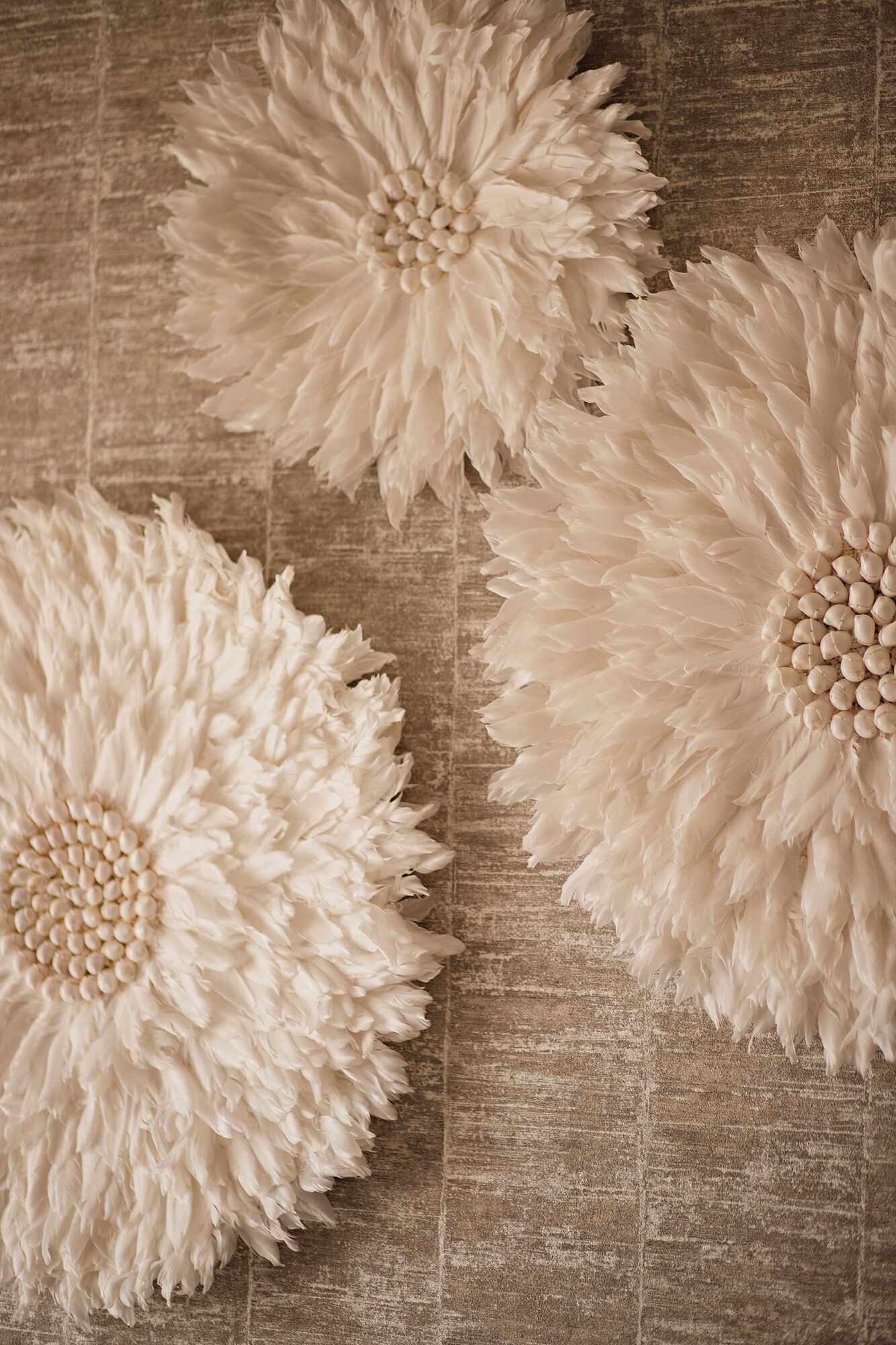 Tres flores blancas grandes, esponjosas y decorativas sobre una superficie de madera con textura.