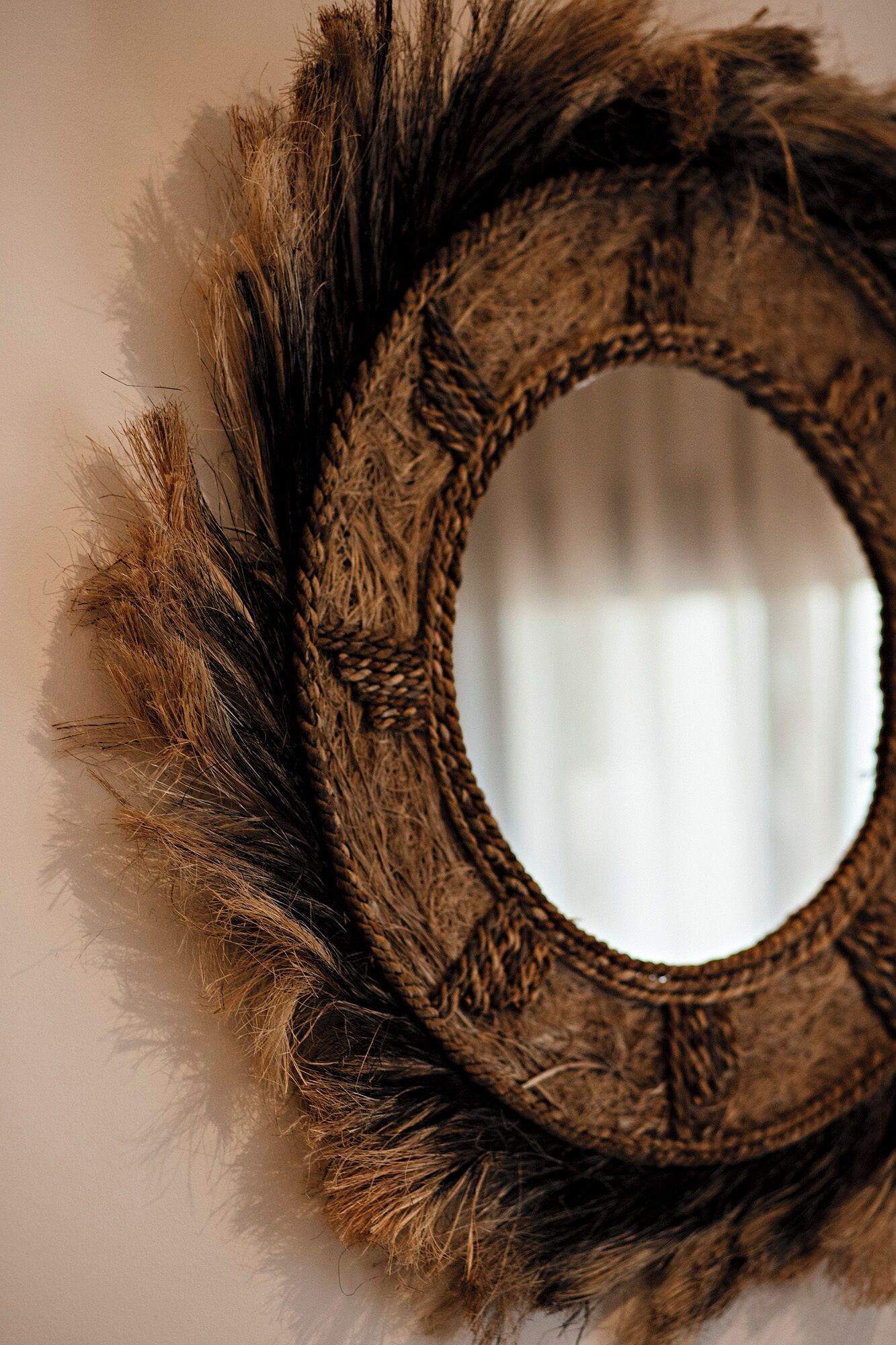 Un miroir rond orné d’un bord texturé, rappelant la fourrure.