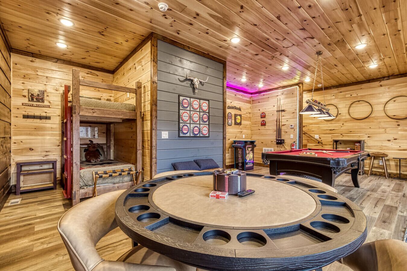 Una cabaña de madera acogedora con mesa de billar, mesa de futbolín y una gran mesa redonda con sillas.