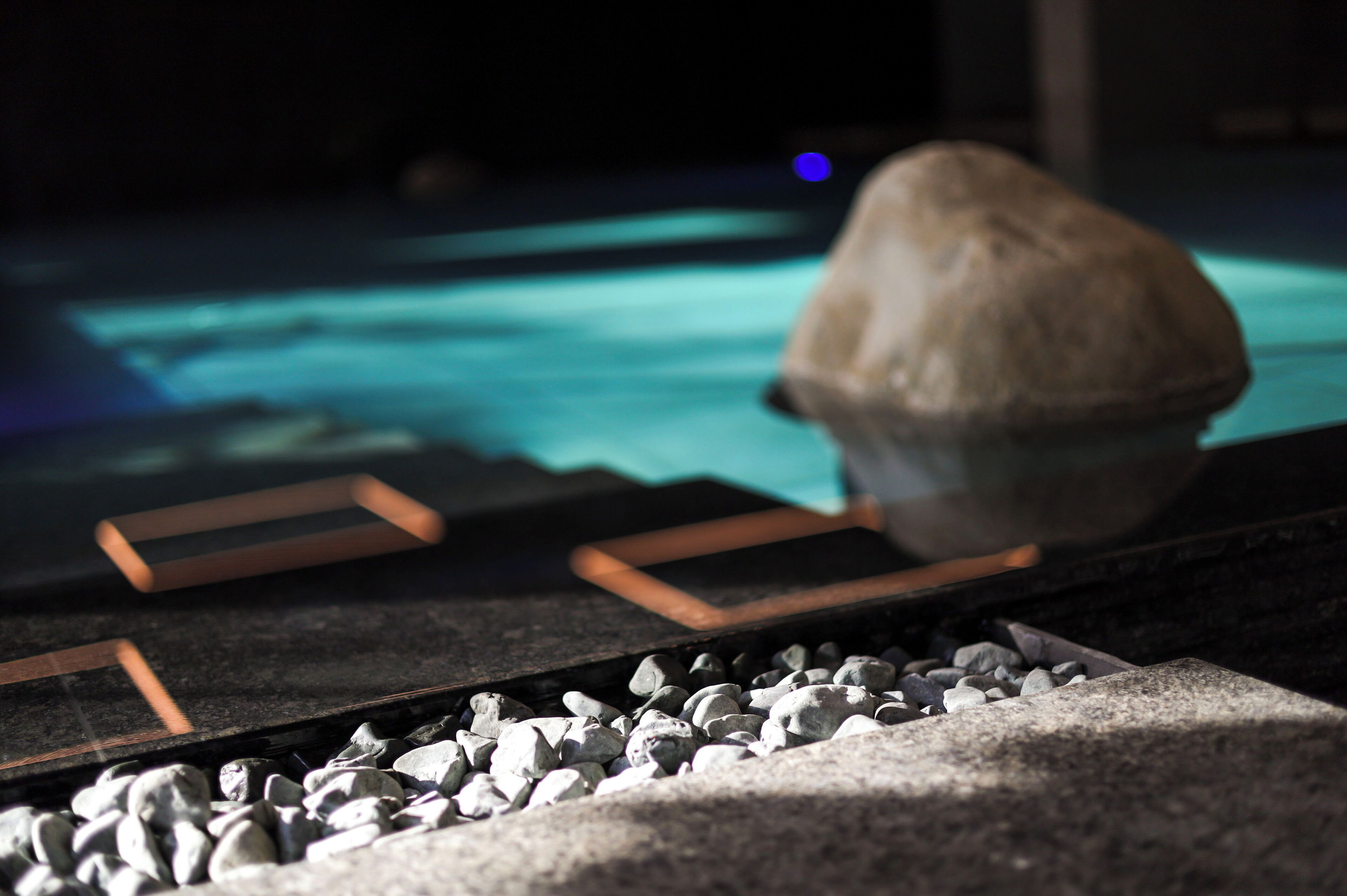 A rock on a platform with a pool in the background.