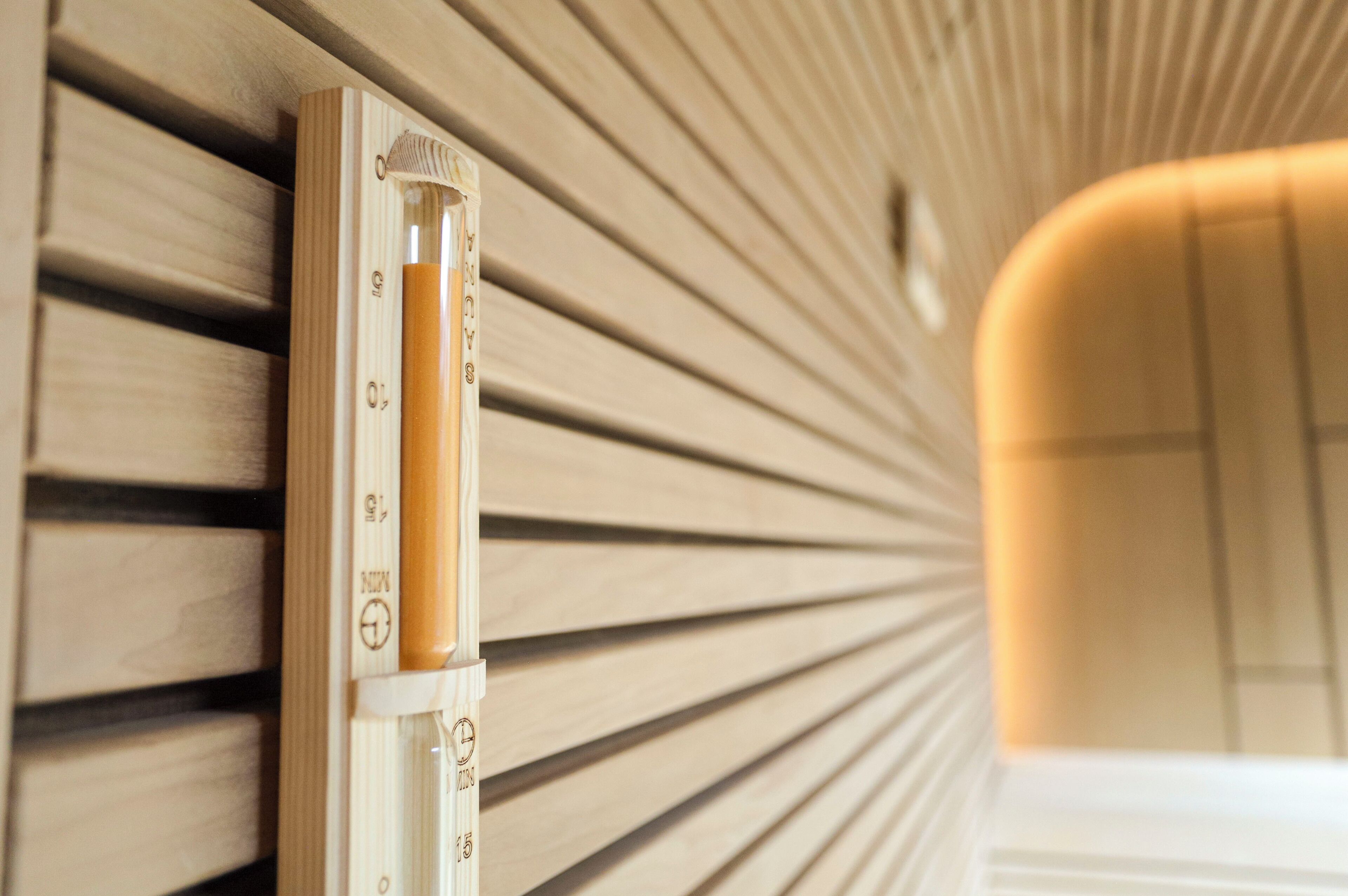 Un parete di legno con un elemento verticale, forse una lampada, e una nicchia con una luce calda.