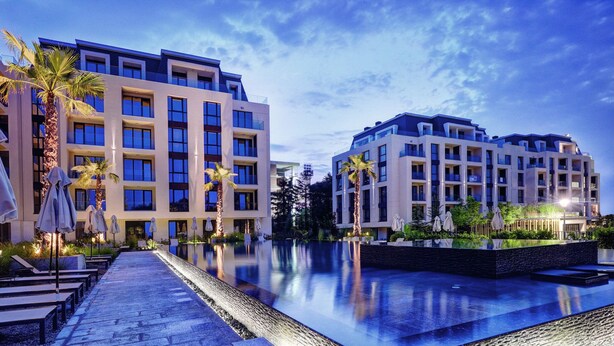 Un hotel moderno con piscina, area salotto all'aperto e palme.