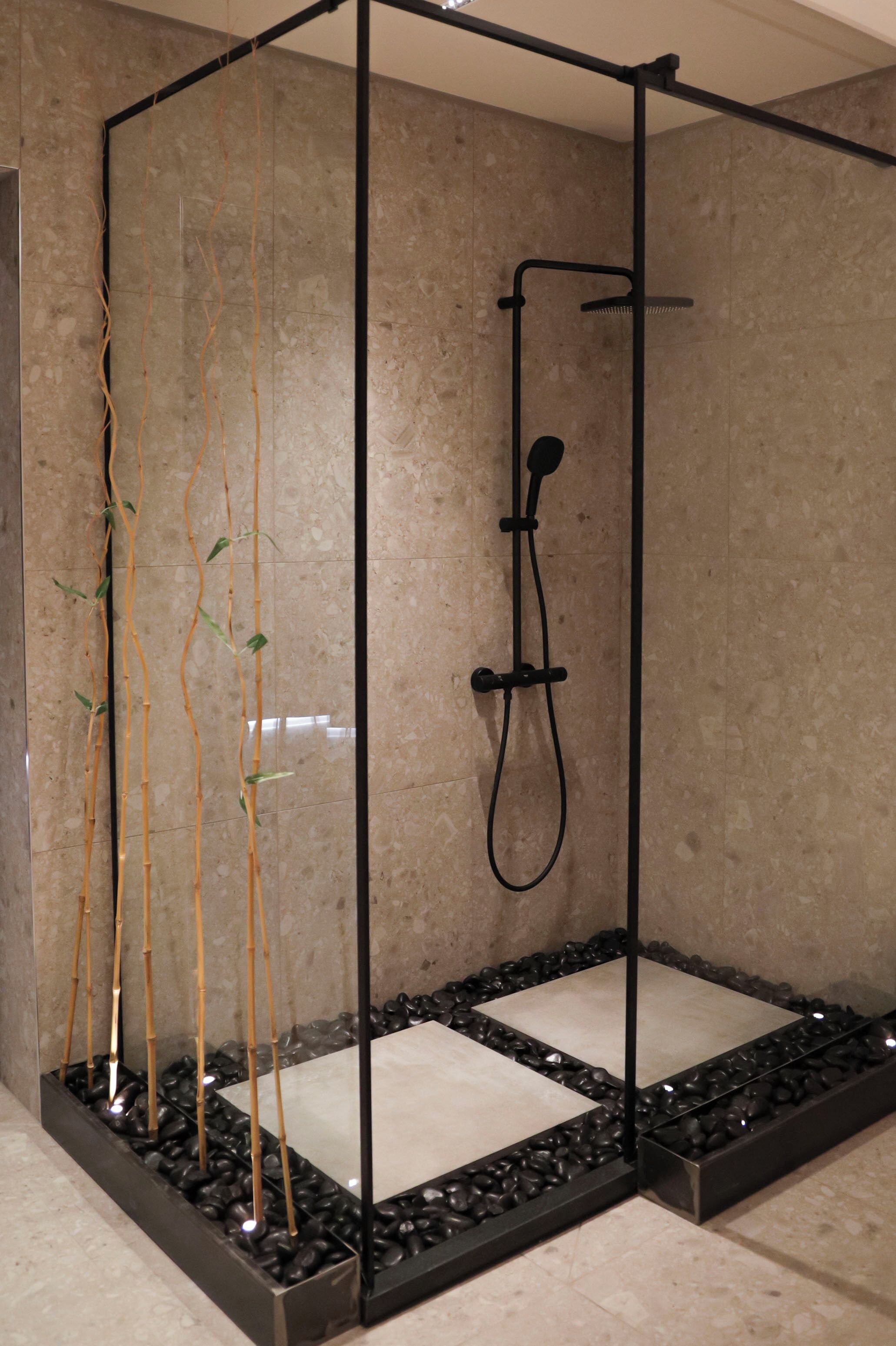 Une cabine de douche moderne dotée d’une porte en verre, d’un cadre noir et d’un sol carrelé.