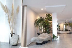 A modern lobby with a stone sculpture, tall plants, and a striped column. - Azur Premium Resort (Saints Constantine and Helena)