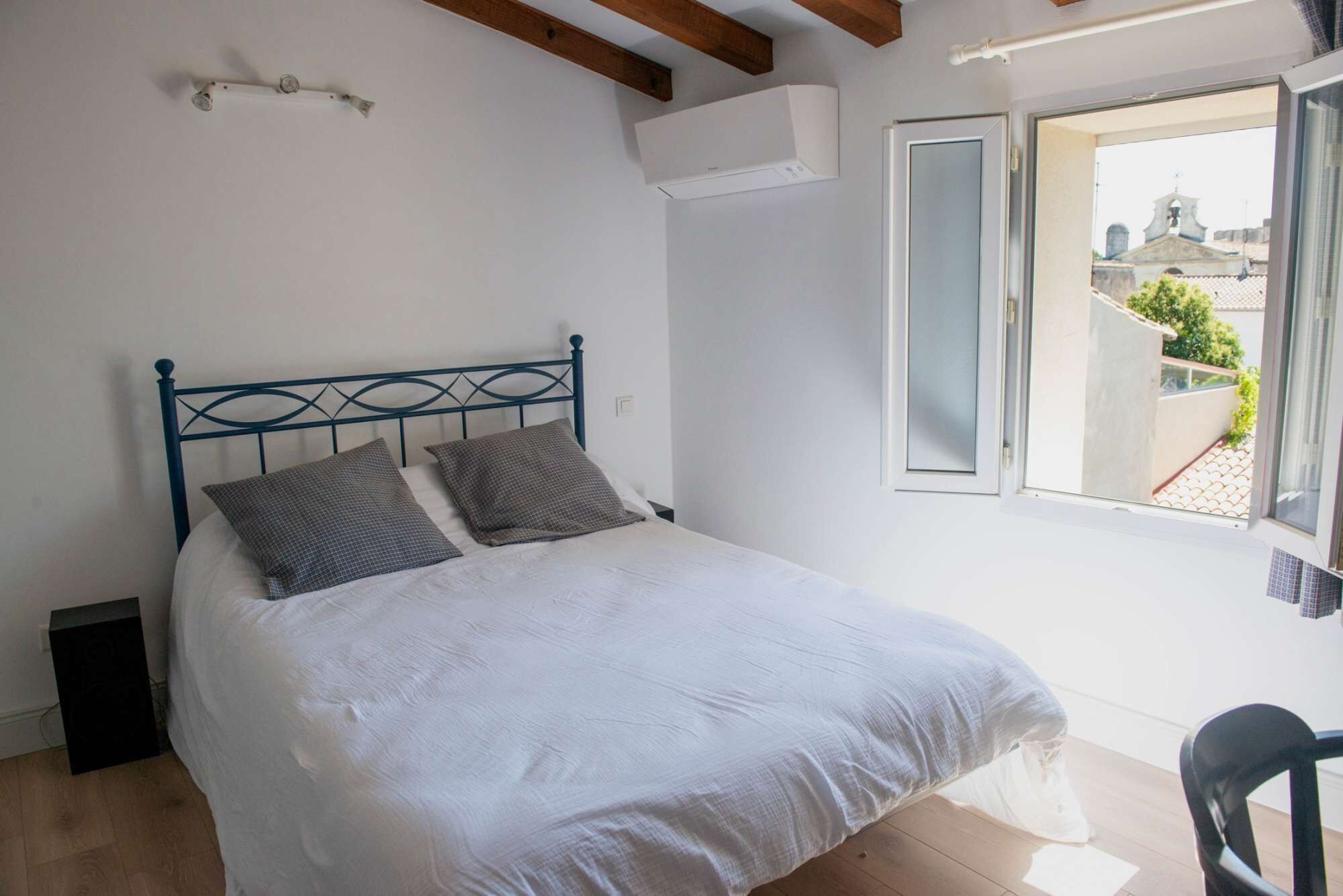 Een slaapkamer met een bed, een raam en een stoel.