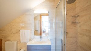 Ein modernes Badezimmer mit einer gläsernen Duschkabine, einem weißen Waschbecken und einer sichtbaren Toilette.