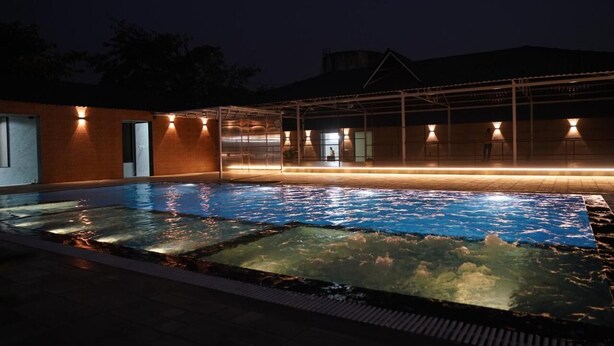 Una piscina con fondo in vetro, circondata da un'area coperta con luci.