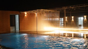 Una piscina al coperto con parete di vetro, una porta e un soffitto con luci.