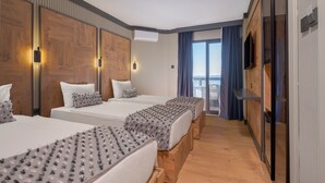 Une chambre d’hôtel avec trois lits, une télévision et un balcon avec des rideaux.