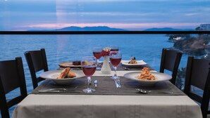 Une table dressée pour un repas, avec une vue sur la mer et les montagnes en arrière-plan.